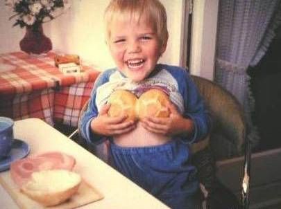 1976 Ford F-150 - A young boy is sitting at a table and holding two bread rolls to his chest.