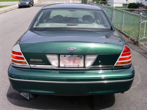 2001 Ford Crown Victoria - The rear of a green 2001 Ford Crown Victoria LX is shown, with a Massachusetts license plate and the 'Quirk' badge visible.