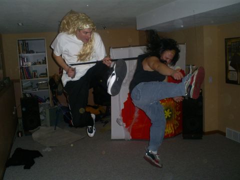 1977 Ford F-150 - Two individuals engage in a playful karate-themed pose, one sporting a blonde wig and the other mid-kick.