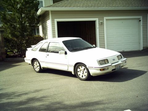 1975 Ford Torino - A white coupe with a spoiler is parked in front of a residential garage.