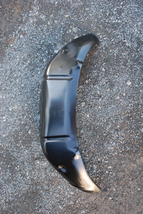 1996 Ford Bronco - A black metal inner fender liner is shown lying on a gravel surface.