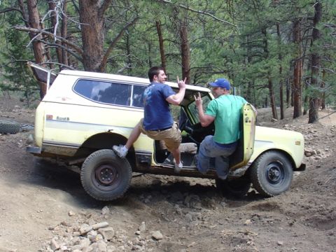 1996 Ford Bronco - Two men enjoy a ride in a yellow International Harvester Scout II as it navigates a rocky, wooded trail.