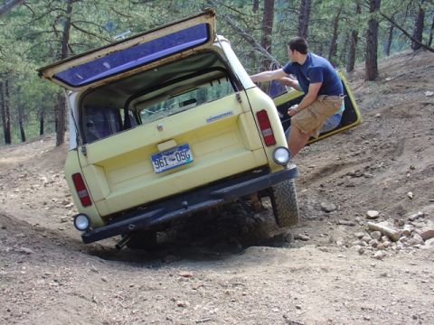 1996 Ford Bronco - An International Scout is stuck on a dirt trail with its doors open.