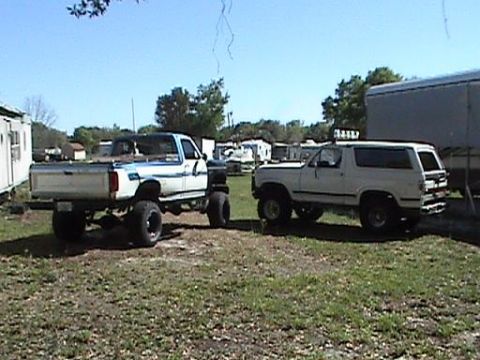 1986 Ford Bronco - A white 1987 Ford Bronco is parked next to a lifted pickup truck in an outdoor lot.