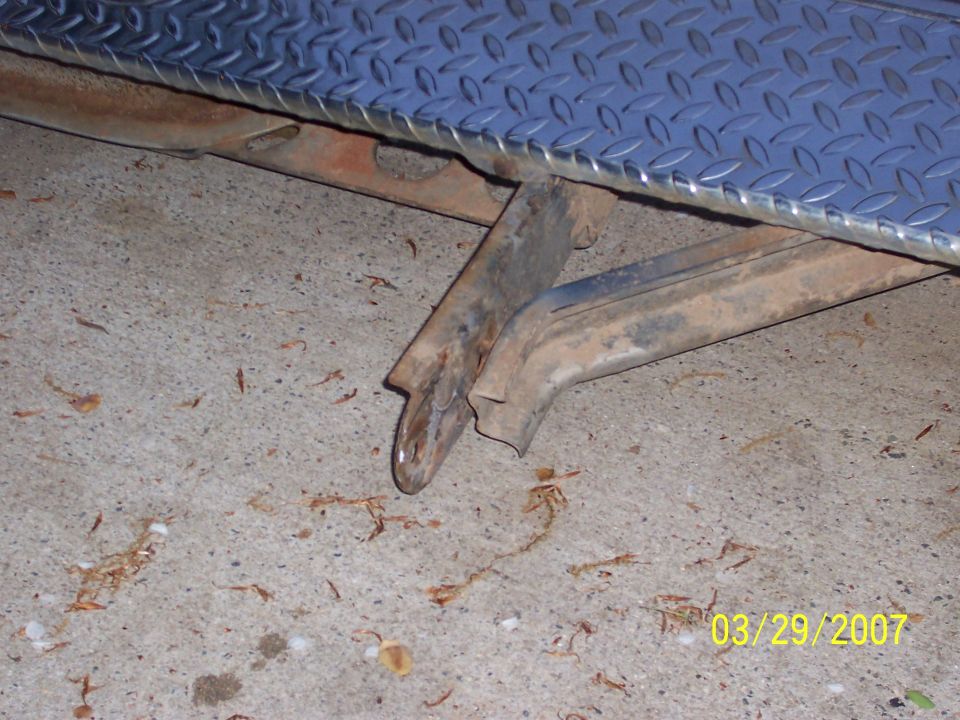 rusted metal frame with diamond plate above, on concrete floor