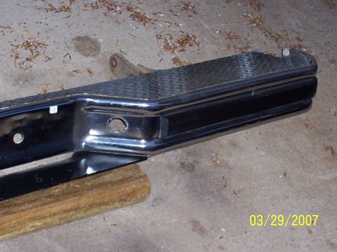 1988 Ford Bronco - Close-up of a chrome bumper part with a diamond plate step, resting on a wooden block.