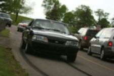 1989 Ford Mustang - A black 1989 Ford Mustang is seen on the road, surrounded by other vehicles.