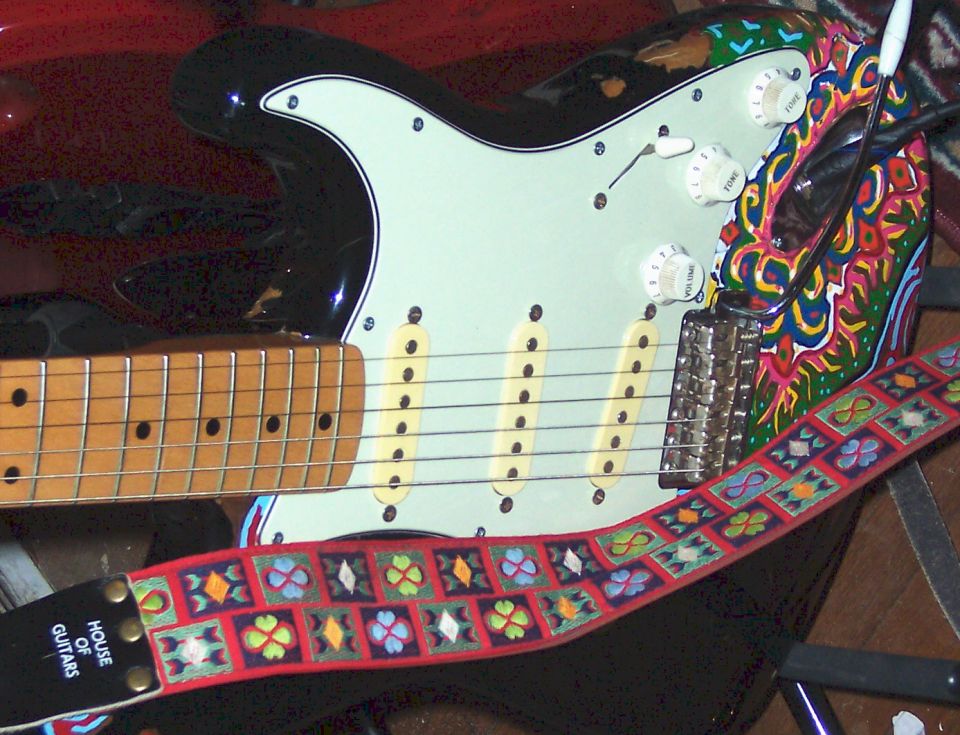 Black electric guitar with mint pickguard and embroidered House of Guitars strap