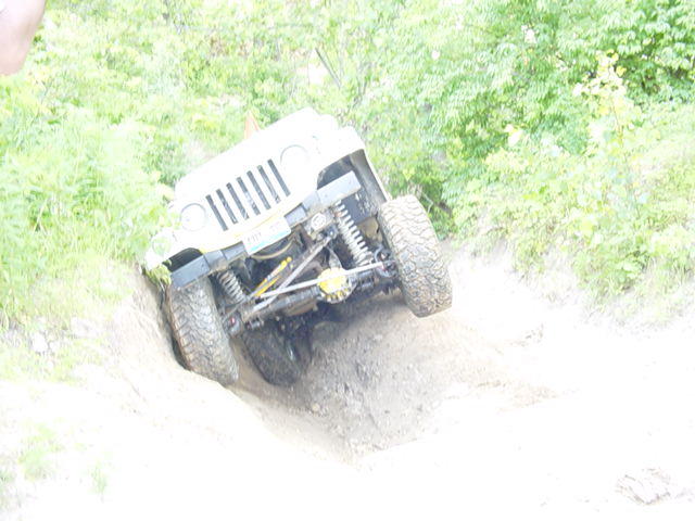 Jeep Wrangler TJ climbing steep dirt incline, front grille and suspension visible