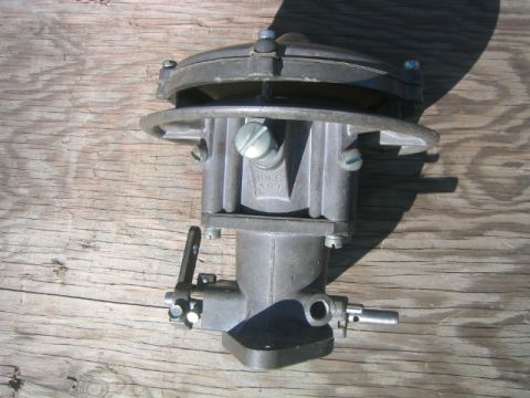 1973 Ford F-100 - A close-up view of a Holley carburetor, identified by visible markings, resting on a weathered wooden background.