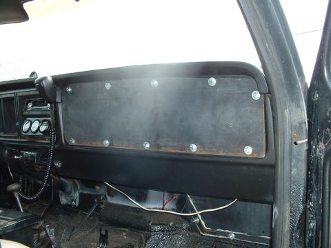 1978 Ford Bronco - The interior of a vehicle shows a modified dashboard with a large, bolted wooden panel covering the center section.