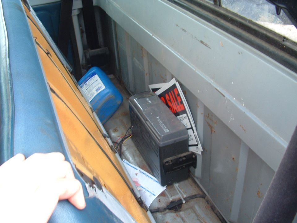 Interior of a truck bed with a blue jug, Sony device, and "FOR SALE" signs