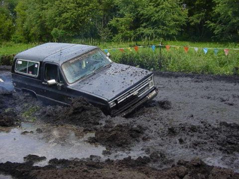 1992 Ford Bronco - This black SUV is deeply stuck in a muddy off-road course.