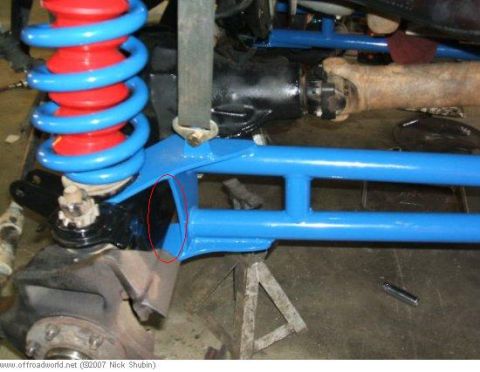 1984 Ford Bronco - Close-up view of custom blue suspension components, including a coilover shock with red and blue springs.