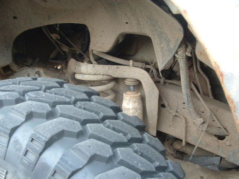 1983 Ford Ranger - A close-up view of a truck's suspension system and a large, knobby tire, covered in mud.