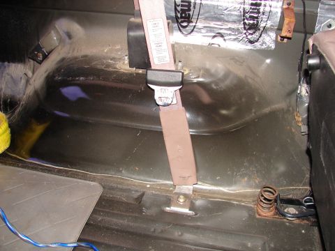 1996 Ford Bronco - Interior view of the rear wheel well area in a 1996 Ford Bronco, showing the seatbelt and sound deadening material.