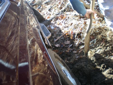 1996 Ford Bronco - A maroon 1996 Ford Bronco is stuck in the mud, with a person using a shovel to dig it out.