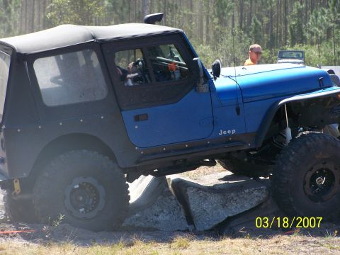 1989 Ford Bronco - A blue Jeep Wrangler navigates an obstacle course with another Jeep visible in the distance.