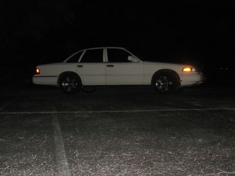 1997 Ford Crown Victoria - Side profile of a white 1997 Ford Crown Victoria sedan parked outdoors at night.
