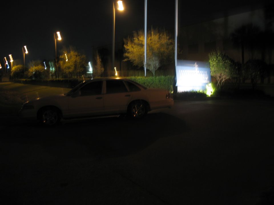 Light-colored sedan parked at night, viewed from the side