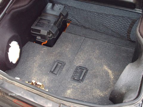 1995 Ford Probe - The trunk of a car contains a battery, a cargo net, and a spare tire well, with two handles on the floor.