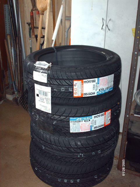 1995 Ford Probe - Four new tires are stacked in a garage, with tools visible in the background.