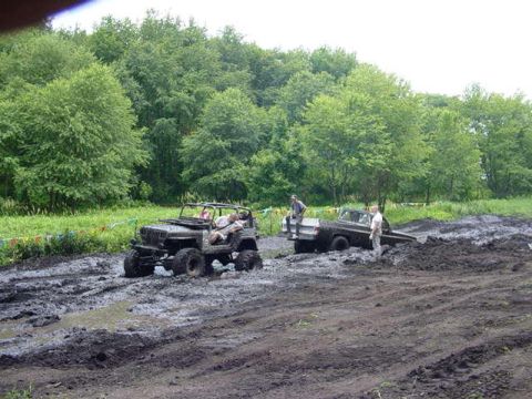 1992 Ford Bronco - Two off-road vehicles are stuck in deep mud during an event.