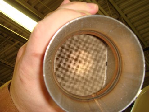 1996 Ford Bronco - A hand holds a catalytic converter, revealing its internal honeycomb structure.