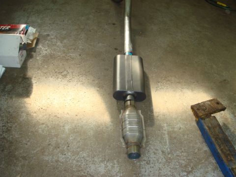 1996 Ford Bronco - Exhaust system part, including a catalytic converter and muffler, on a concrete floor.