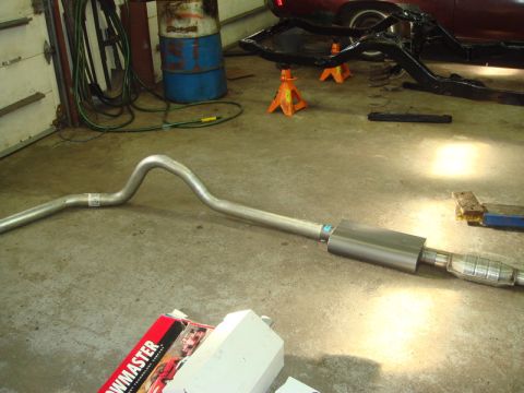 1996 Ford Bronco - A new exhaust system component lies on the concrete floor next to a box for Flowmaster parts.