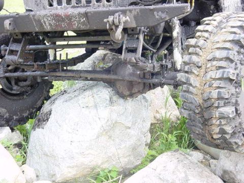 1992 Ford Bronco - Off-road vehicle's front suspension and tire are visible, resting on large rocks.