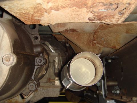 1996 Ford Bronco - Vehicle's catalytic converter and exhaust system components are visible, showing signs of rust on the frame.