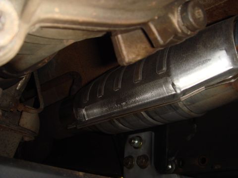 1996 Ford Bronco - Close-up view of the exhaust system, focusing on the catalytic converter and its protective shield.