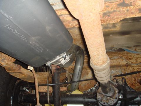 1996 Ford Bronco - Close-up of a Flowmaster muffler and exhaust system components under a vehicle.