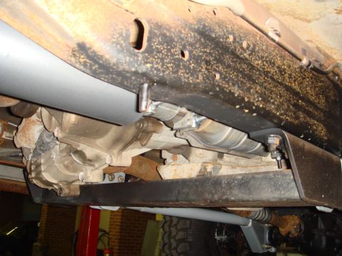 1996 Ford Bronco - Close-up view of the drivetrain and exhaust system of a vehicle, showing various mechanical components.