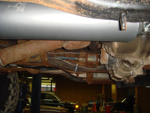 1996 Ford Bronco - Underside view of a vehicle's exhaust system and transmission, showing signs of rust and wear.