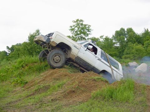 1992 Ford Bronco - This SUV is navigating a steep, grassy incline during an off-road event.