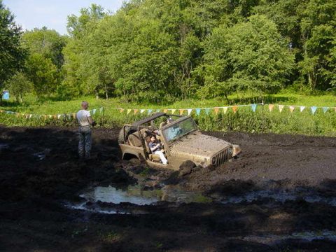 1992 Ford Bronco - A Jeep Wrangler is stuck in a mud pit during an off-road event.