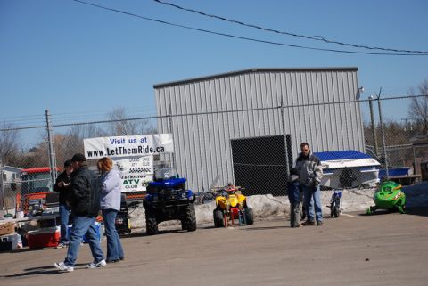 1996 Ford Bronco - Various recreational vehicles, including ATVs and a snowmobile, are parked outside a fenced area with a large metal building.