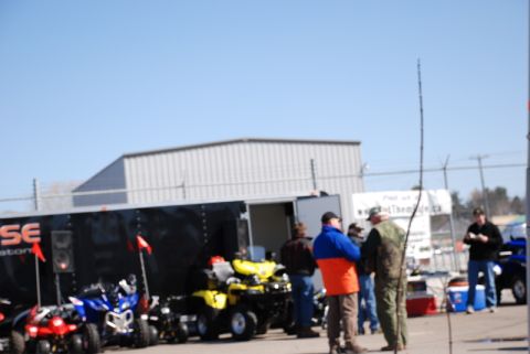 1996 Ford Bronco - ATVs are parked outside a trailer with a group of people nearby on a sunny day.