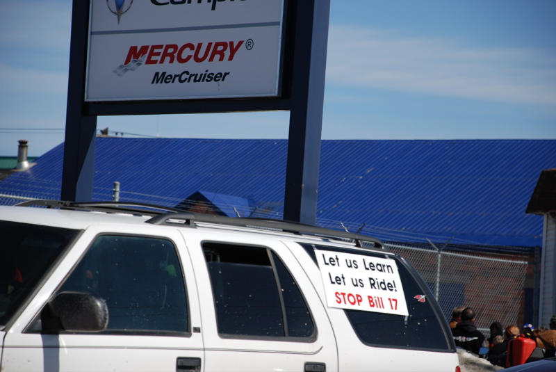 white SUV with sign on window saying 'Let us Learn Let us Ride! STOP Bill 17'