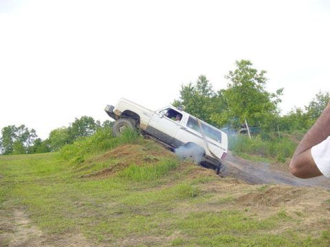 1992 Ford Bronco - A white SUV navigates a steep dirt incline, demonstrating its off-road capabilities.