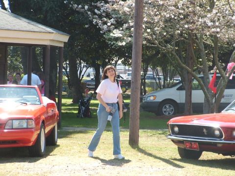 1966 Ford Ranchero - Two red cars are parked outside with a woman standing in the middle.
