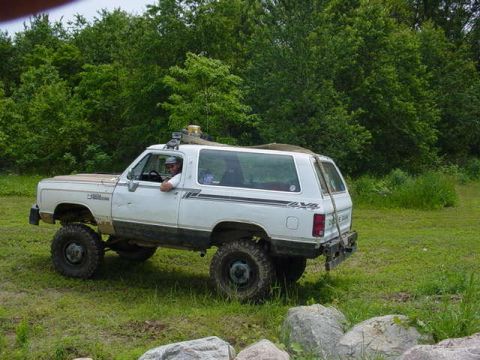 1992 Ford Bronco - White Dodge Ramcharger with off-road tires parked on grass, driver visible.