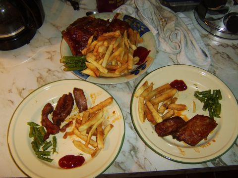 1989 Ford Bronco - A meal consisting of french fries, ribs, and green beans is served on three plates.