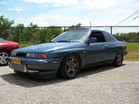 2006 Mazda 6 - A blue coupe is parked next to a red car, an exposed intercooler and aftermarket wheels.