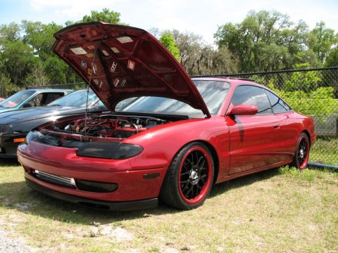 2006 Mazda 6 - Red coupe with hood open, parked next to a black car. Aftermarket wheels and lowered suspension visible.