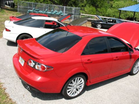 2006 Mazda 6 - A red 2006 Mazda 6 sedan is parked outdoors with its hood up, alongside other vehicles.