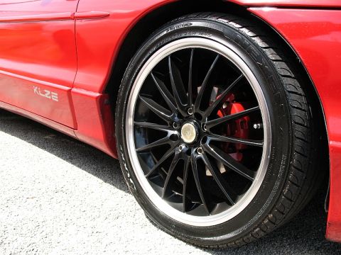 2006 Mazda 6 - Close-up of a custom wheel and tire on a red car's fender, showing a 'KLZE' badge.
