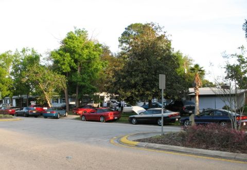 2006 Mazda 6 - A collection of vehicles are parked in a lot, with trees and houses visible in the background.
